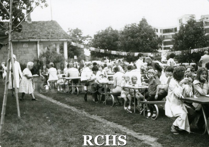 Black and white photograph of people sitting at tables eating at the Tallman Arts Exhibit.