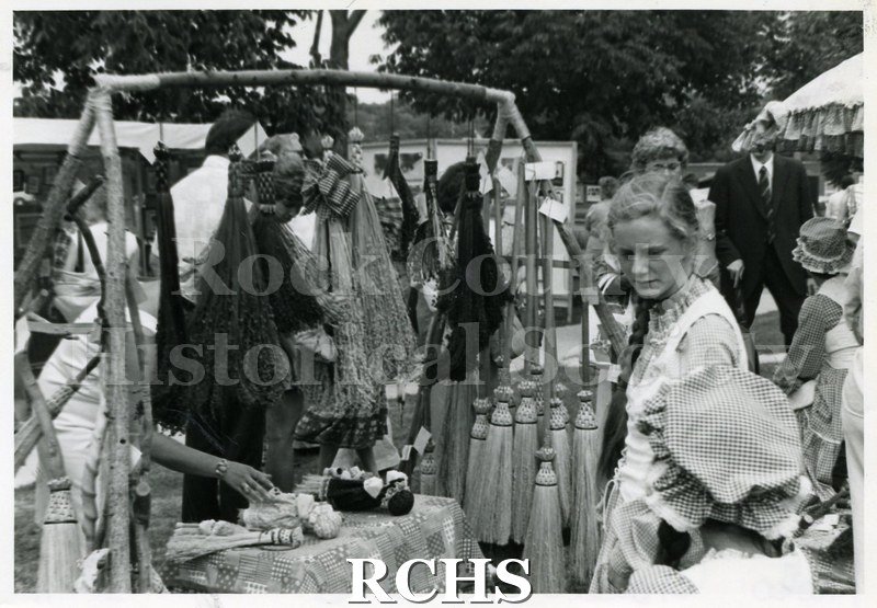 Black and white photograph of the 1981 Tallman Festival. People are looking at an exhibit of brooms.