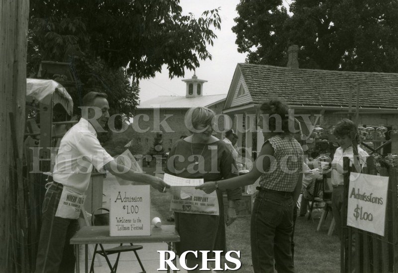 Black and white photograph of the 1983 Tallman Festival. Shows people paying the admission of $1.00 and receiving a map of the grounds. N83013 Strip.