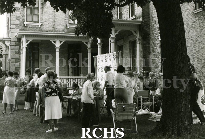 Black and white photograph of people on the grounds of the Tallman House looking at the quilt exhibit.