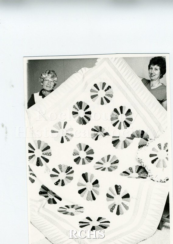 Black and white photograph of Ann Murphy and Faye Bidwell holding a quilt.
