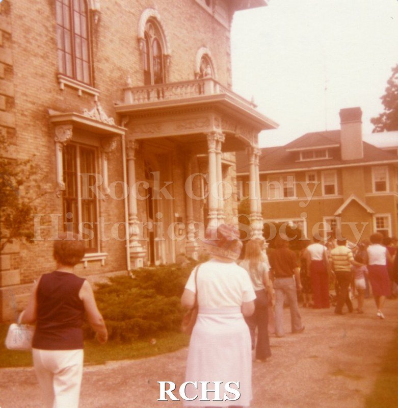 Historic image of Colored phhotograph of the 1977 Arts & Craft Fair. Shows people strolling on the grounds of the Tallman House.