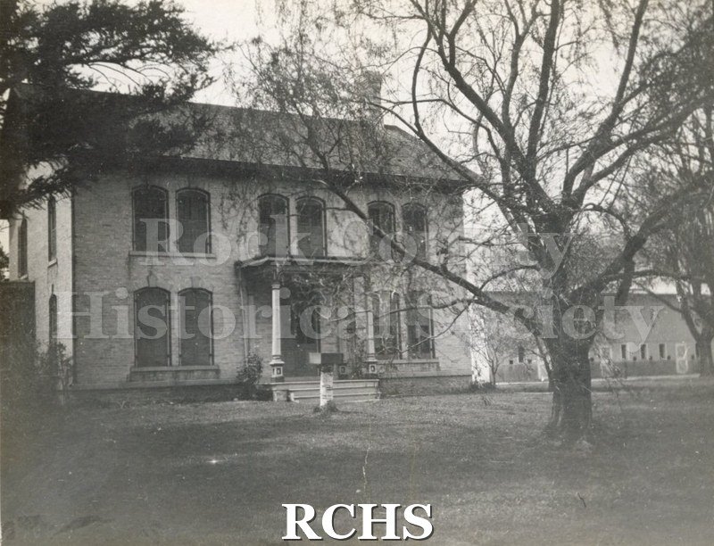 Black and white photograph of an unidentified two story brick house with a barn in the background. Could be Craighurst.