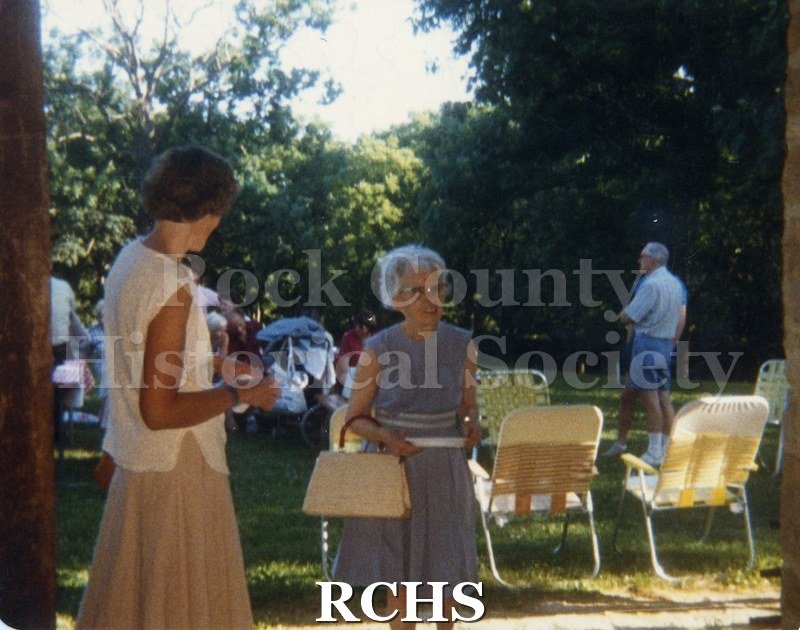 Color photo of Ruth Hughes standing near several chairs. On back "Ruth Hughes 15 June 1987 Bea Seitz, Photographer".