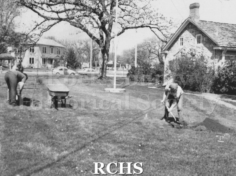 Black and white photograph of two unidentified people working on a lawn.