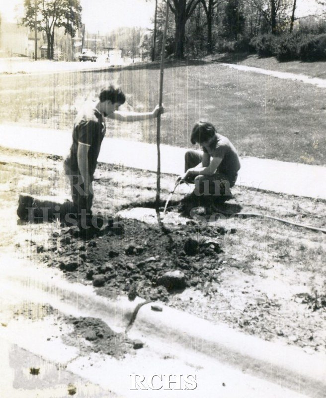 Black and white photograph of two unidentified young men planting a tree. On back "Craig, Parker, Milton FFA at "Plant-in" May 17, 1975".
