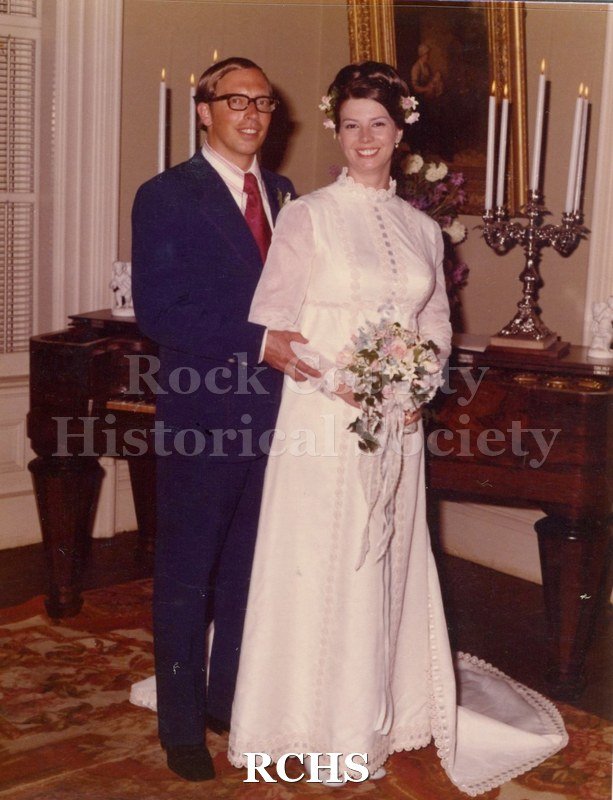 Historic image of Color photogrpah of bride and groom standing near the piano.