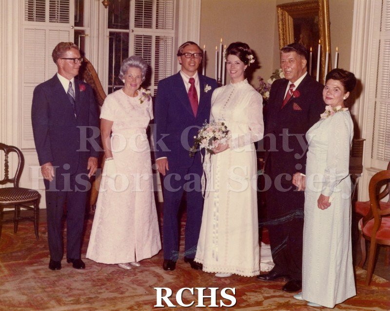 Color photo of bridal couple with their parents.