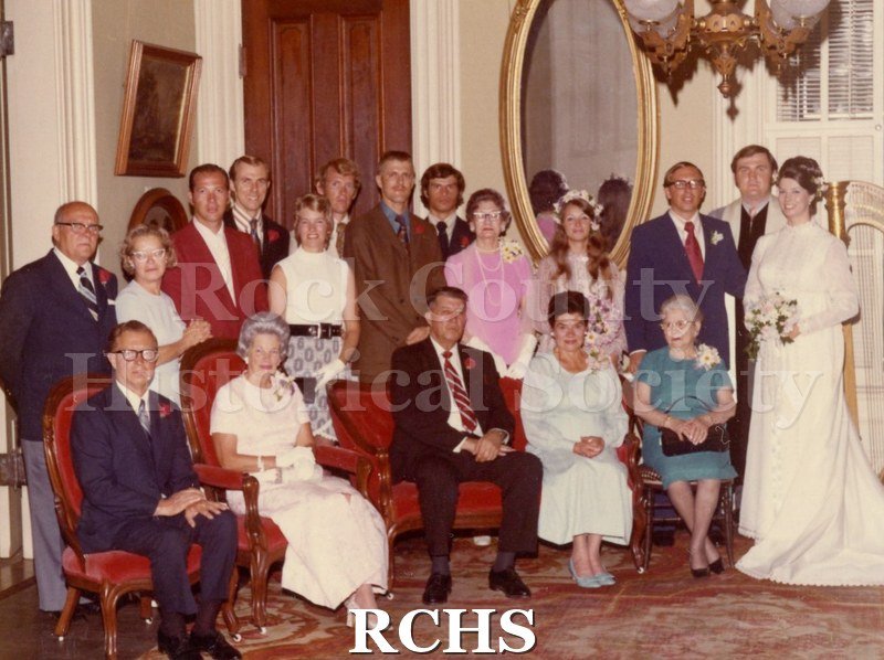 Color photo of bridal couple with their families.