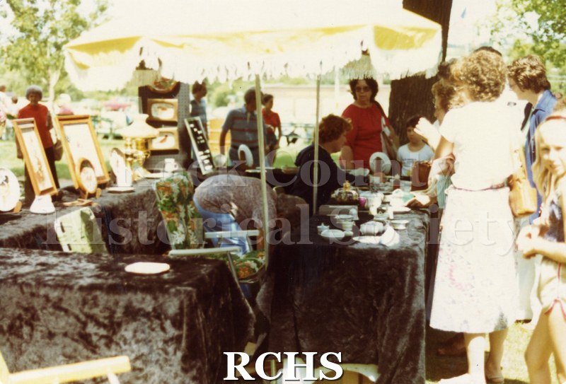 Colored photograph of people looking at an exhibit of dishes.