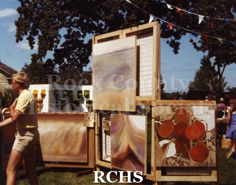 Colored photograph of a display booth featuring paintings.