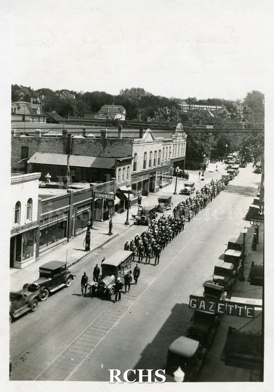 Black and white photograph of the funeral procession for Ralph J. Kamps. A funeral procession goes down Milwaukee Street after the funeral of the Post Commander.