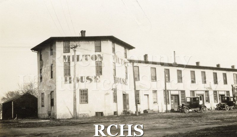 Black and white photograph of the Milton House. Shows 1930 era cars parked in front of it.