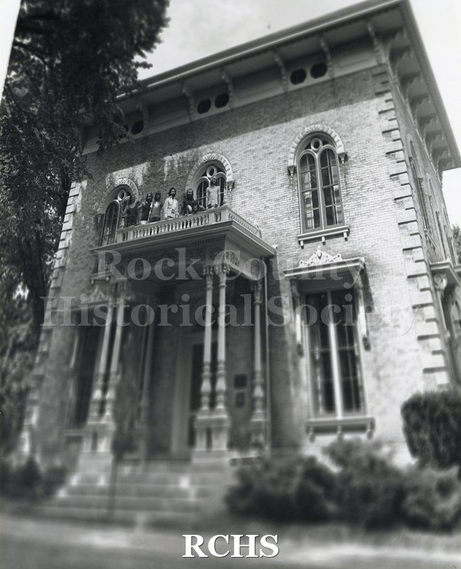 Black and white photograph of Orfordville Dump Truckers-Rock Group. Shows a band standing on the balcony of the Tallman House.