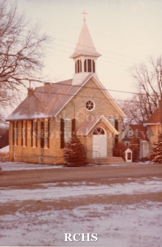 Color photo of Immanuel Lutheran Church-Hanover, WI. Shows a brick church with a belltower and cross.
