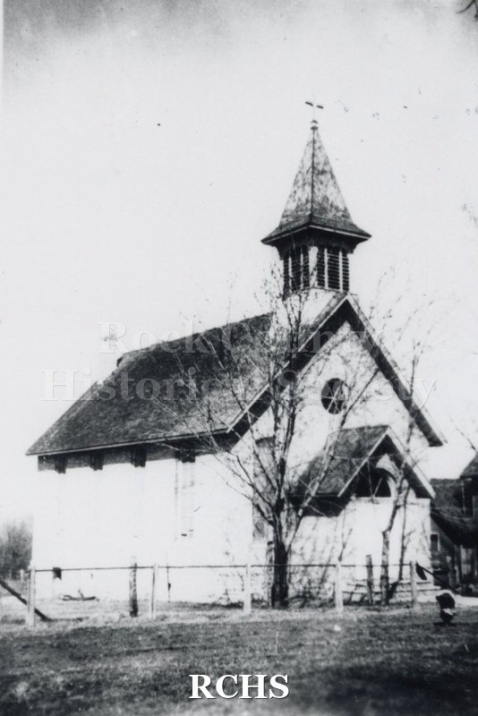 Black and white photograph of Immanuel Lutheran Church. Shows a one story church with a belltower and a cross on top.