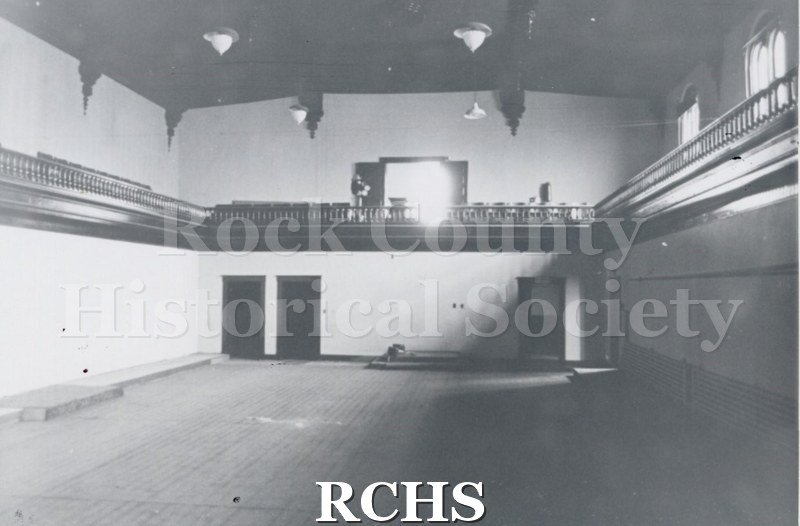 Black and white photograph of the Court Street Methodist Church. Shows the interior of a room, showing two doors on the left and a balcony above.