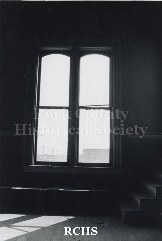 Black and white photograph of Myers Block-Old Armory, Janesville, WI, interior view, showing a wall with two arched windows.
