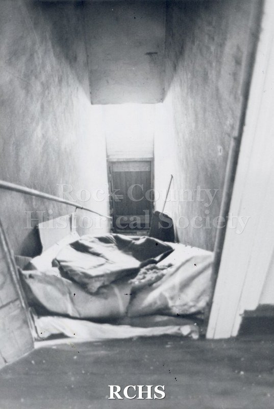 Black and white photograph of Myers Block-Old Armory, Janesville, WI, interior view, showing the stairs. There is a tarp on the stairs at the top.
