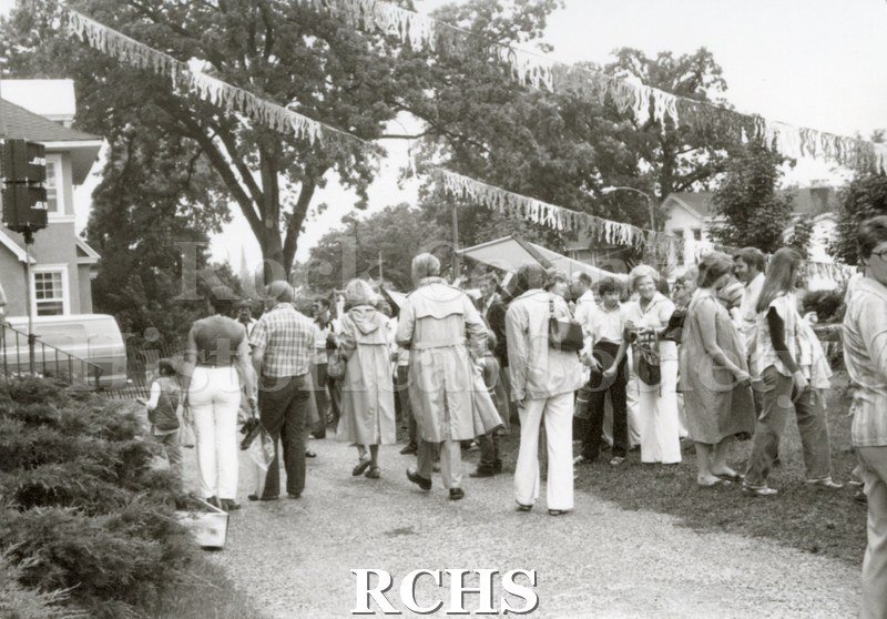 Black and white photograph of the Tallman Arts Exhibit. Shows many people walking along and some standing on the exhibit grounds.