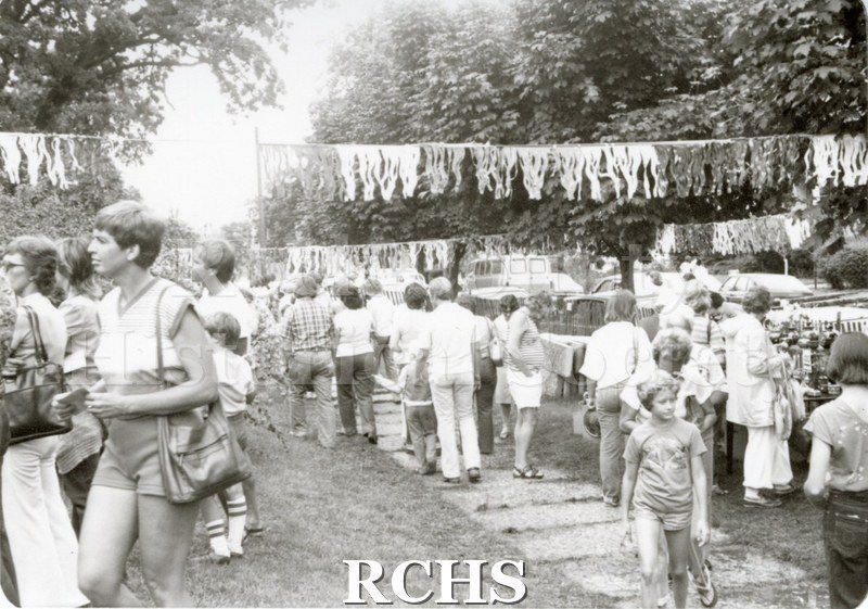Black and white photograph of theTallman Arts Exhibit. People are strolling along the walk in front of the exhibits at the Tallman Arts Festival.