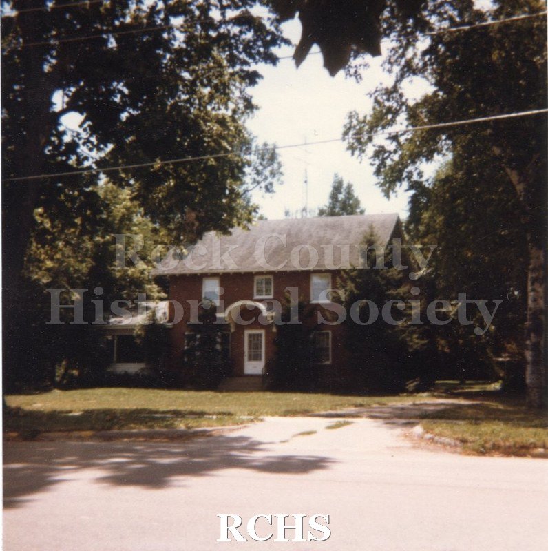 Color photo of the President's Home on Milton College campus. House is a two story brick with a porch. Transcription.