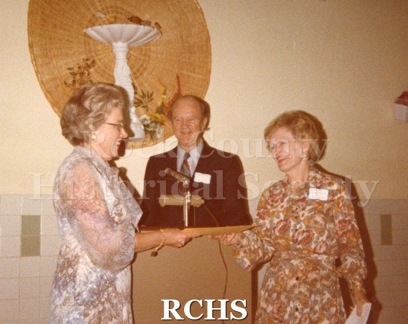 Color photo of Marge Kroehler, Rev. H. Walz, and Dorothy Gilbertson. The two women are standing in front of a podium and Rev.Walz is standing behind it.