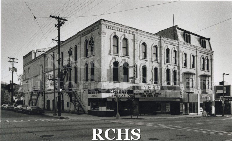 Historic image of Black and white copy print of the Myers Theater with a marque featuring "Elks Club Serving Noon Lunch Mon thru Fri". On the left is M.F.