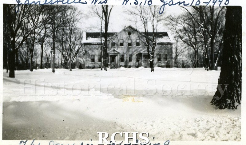 Black and white photograph of the Wisconsin School for the Blind, The Music Building is a two story building with snow on the ground. On top: "Janesville, Wis.