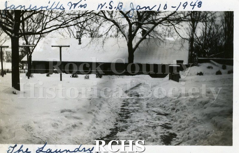 Black and white photograph of the Wisconsin School for the Blind Laundry, a brick one-story building with its roof covered in snow. On top: "Janesville, Wis.