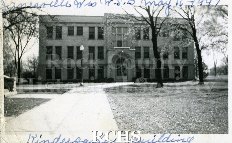 Black and white photograph of the Wisconsin School for the Blind Kindergarten Building, a three-story brick building with an arched doorway.