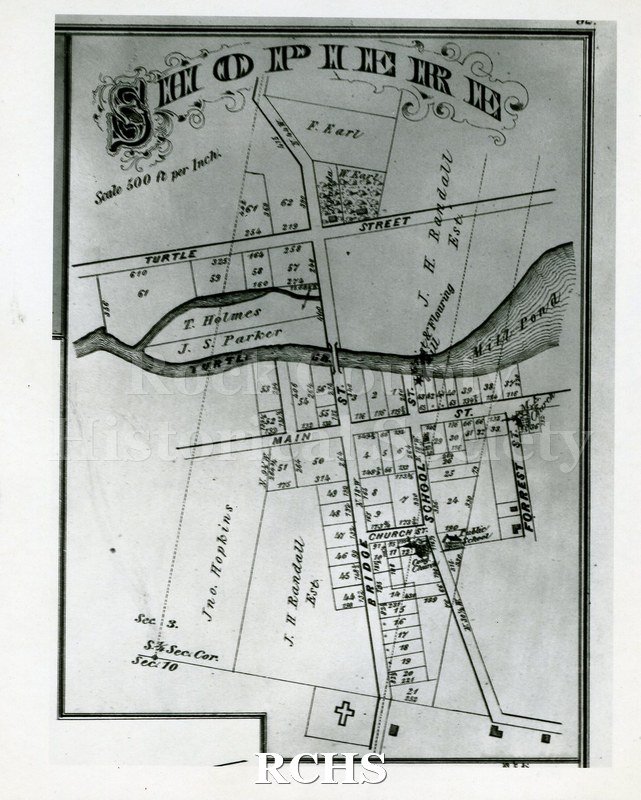 Black and white photograph of a print of a section of a plat map of Shopiere with Turtle Street and Main Street visible and Turtle Creek and Mill Pond between the.