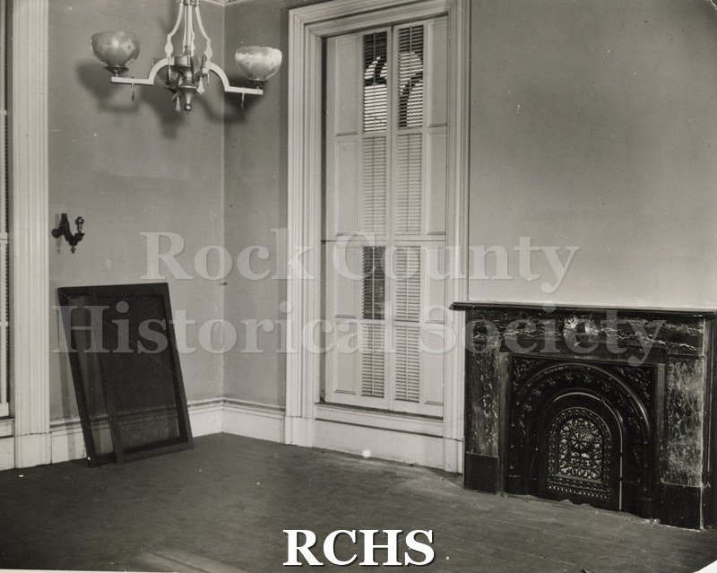 Black and white photograph of the Lincoln bedroom showing the fireplace and windows. There is no furniture in room.
