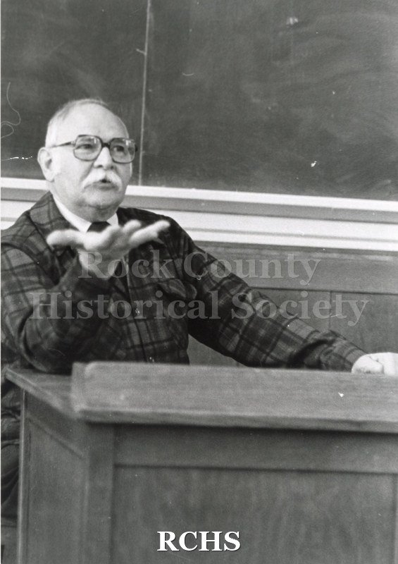 Black and white photograph of Robert H. Inmann wearing a plaid shirt while lecturing.