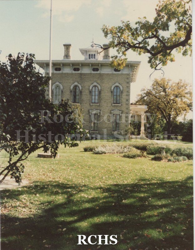 Color photo of the Tallman House with the flagpole in the front and shadows on the grass.