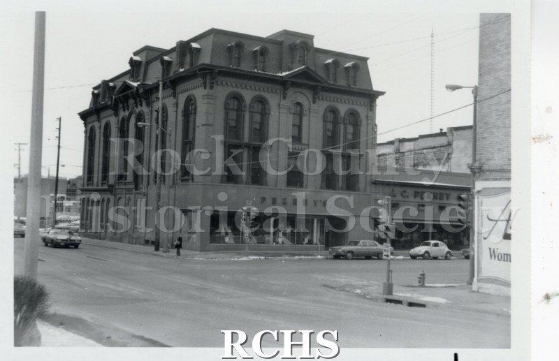 Black and white photograph of four story building housing Penney's on the ground floor.