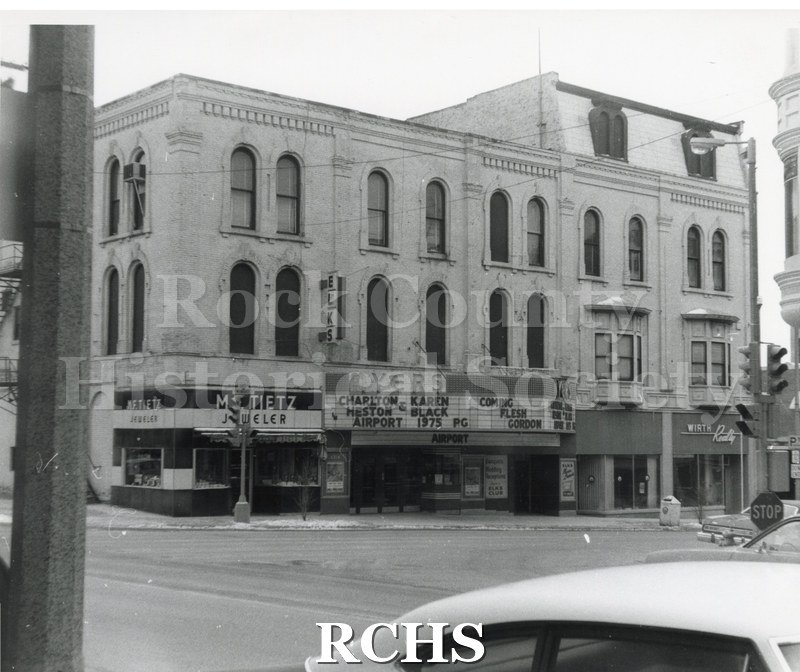 Historic image of Black and white copy print of the Myers Theater with a marque featuring Charlton Heston and Karen Black in Airport 1975 PG. On the left is M.