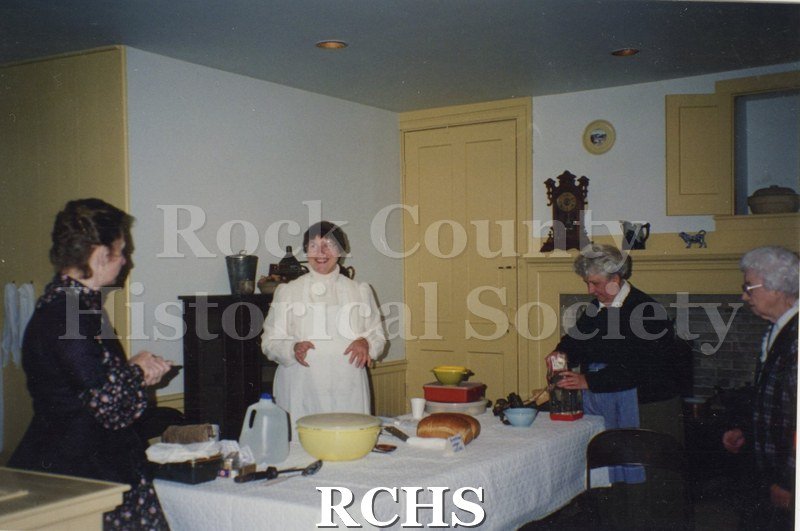 Color photo of Joni Jarstad, Judy Armstrong, Arlene Ledger, and Mable Latzher standing around a table where bread is being made.