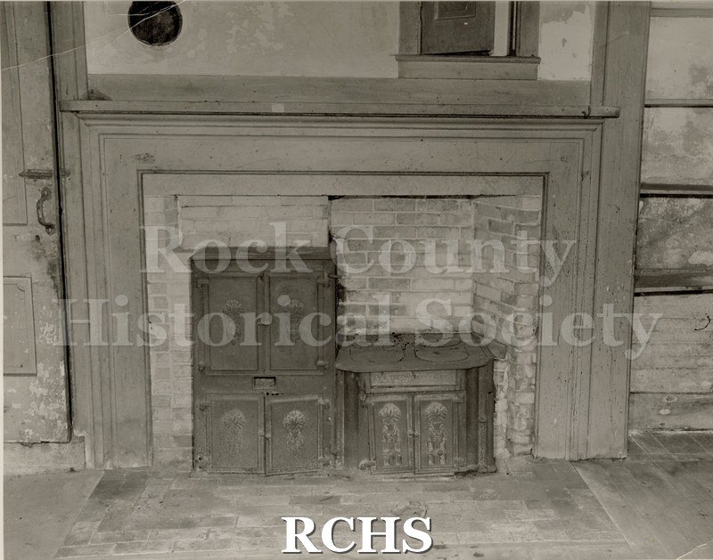 Black and white photograph of the Tallman House kitchen showing the brick fireplace with stove.