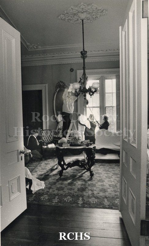Black and white glossy photograph of four women cleaning in the Tallman House.
