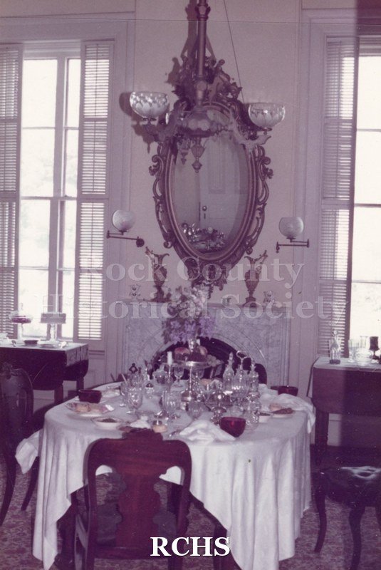 Color photo of the dining room in the Tallman House. The table is set with china, silverware and other objects.