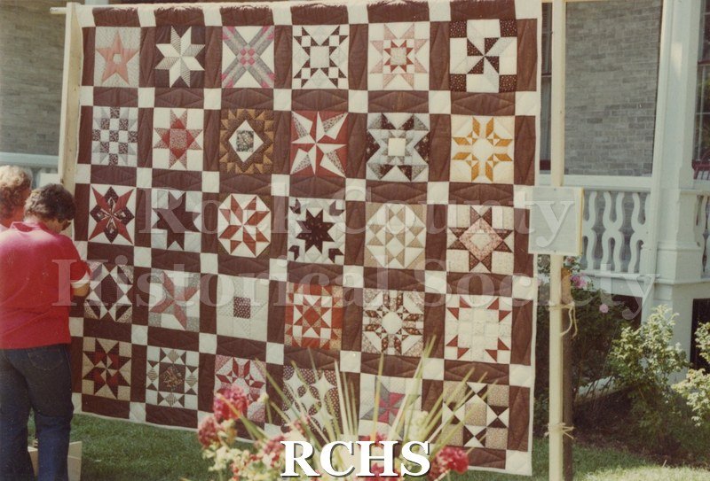 Color photo of the "Star Sampler" quilt made and raffled by members of the Rock Valley Quilters Guild and displayed by them at the 1982 Tallman Festival.