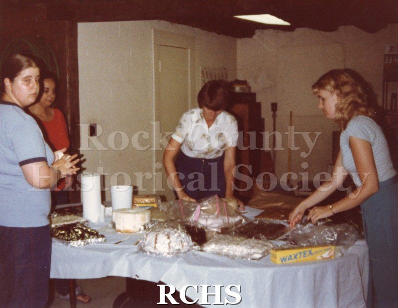 Color photo of several women volunteers preparing cakes for the Tallman House festival.