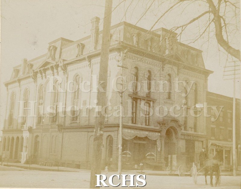 Black and white photograph of Court Street Methodist Church, Janesville, WI, a three story building. There is a horse and buggy on the street in front of it.