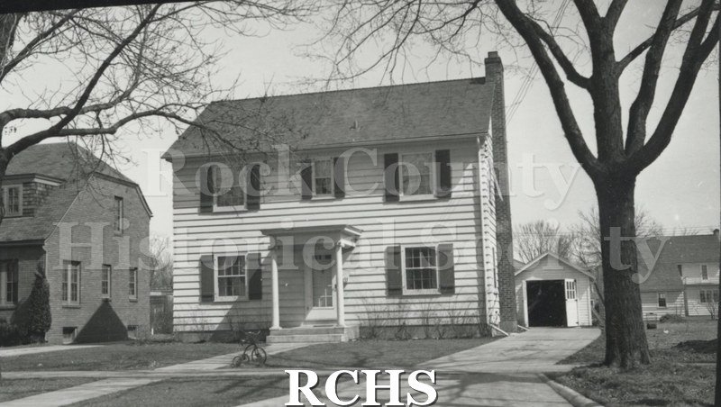 Black and white photograph of Robert L. Jacobs' home, a two story clapboard house with pillared porch in the middle of the first floor and a one car garage behind.