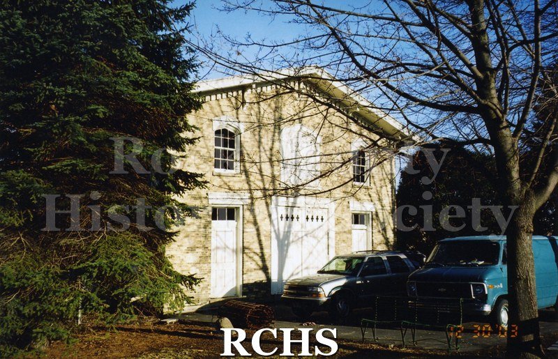 Color photo of the exterior of the Carriage House with two vehicles parked in front.