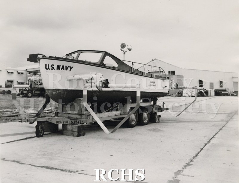 Black and white photograph of "High Pockets" on a trailer. The words: "U.S.Navy" are visible on the front. The word "Baker Hydrofoils" is visible on the backside.