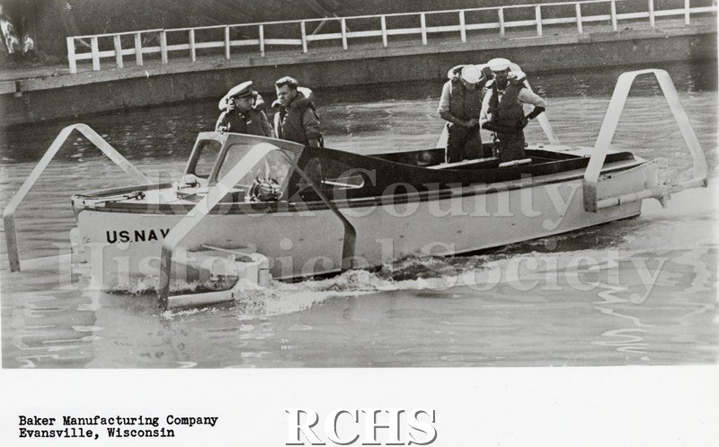 Black and white photograph of "High Pockets" in the water with four men aboard. On bottom: "Baker Manufacturing Company Evansville, Wisconsin".