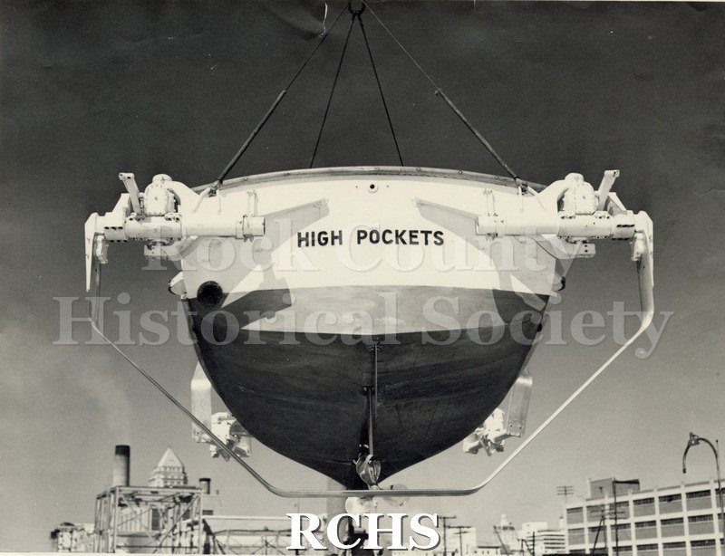 Black and white photograph of "High Pockets". Shows the back end of the boat with the words: "High Pockets" painted on it.