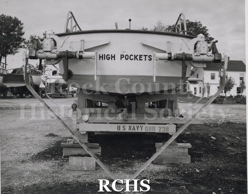 Black and white photograph of "High Pockets" on a trailer. The words "High Pockets" are painted on the back. The trailer has the words: "U.S. Navy ONR 238" on it.